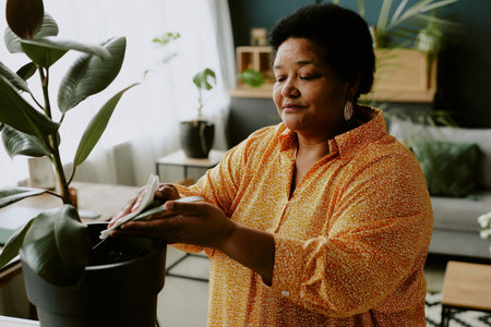 African American woman wiping green rubber fig with calmness on her faceの写真素材