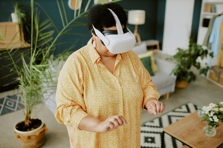 High angle shot of retired African American female gamer writing in air using VR glassesの写真素材