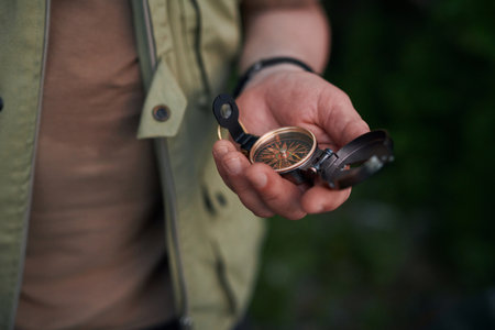 Closeup of unrecognizable male tourist holding compass in hand to find direction
