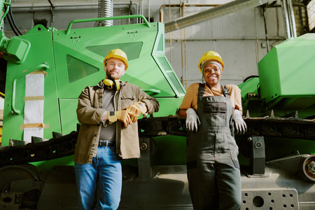 Medium long low angle view shot of African American woman and Caucasian man standing relaxed against...