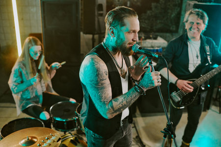 High angle view of Caucasian male vocalist, bassist and female drummer playing punk rock music on...
