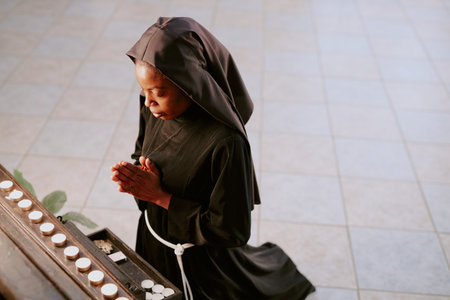 High angle view of young African American nun standing on her knees and praying in front of altar in Catholic churchの写真素材