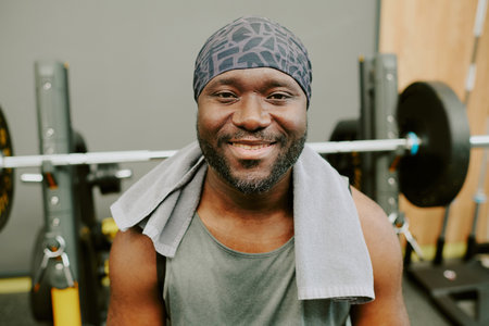 African American man sitting on bench after workout, he smiling and looking at camera