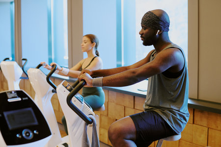 Young biracial couple spending time together in premium fitness club , they doing cardio and man listening to musicの写真素材
