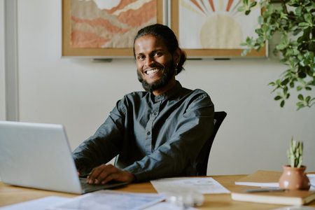Portrait of Indian IT specialist searching information in Internet while sitting in office