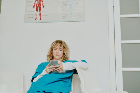 Fatigued young Caucasian nurse doing escapisms with help of smartphone after long night shift