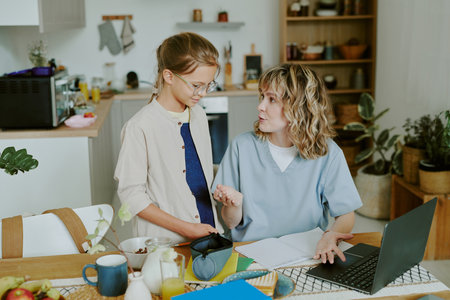 Caucasian nurse mother and daughter discussing school project during breakfast time before work