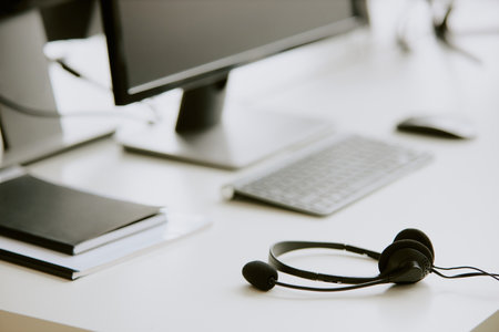 Black wired headphones on white table desk with computer and notebooks on topの写真素材