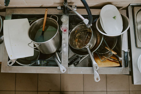Top view of dirty crockery with leftovers in steel kitchen sinkの写真素材