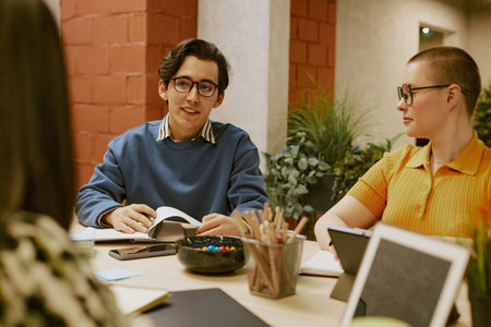 Young biracial man wearing eyeglasses telling about survey results during meeting with marketing...