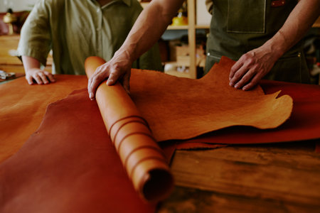 Medium close up of unrecognizable male hands rolling out chocolate leather roll while his clients...
