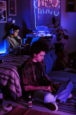 Student chilling in neon dorm room, they playing computer game, drinking beer and listening to music