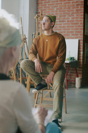 Over shoulder vertical shot of young Caucasian man wearing casual clothes posing for portrait during art classの写真素材