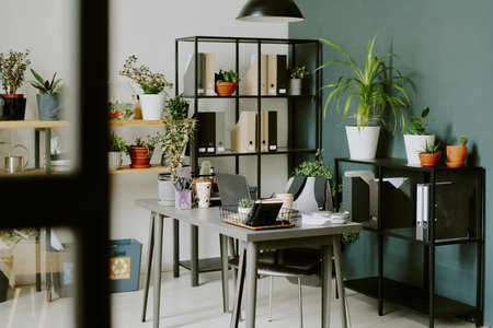No people shot of part of modern biophilic office interior with laptop, office supplies on desk,...