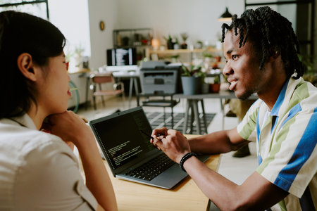 Gen Z African American male and Asian female programmers working on modern software discussing coding issuesの写真素材