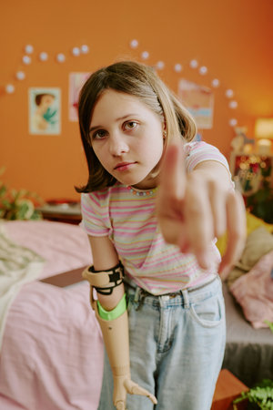 Vertical pov of modern teen girl with disability standing in bedroom turning on camera to record video for blogの写真素材