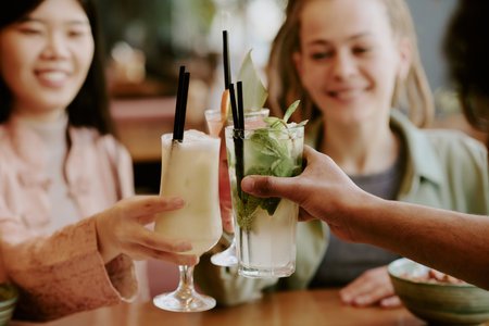 Group sharing refreshing summer drinks garnished with fresh mint and citrus slices in a cozy cafe setting celebrating togetherness and friendship cheersの写真素材