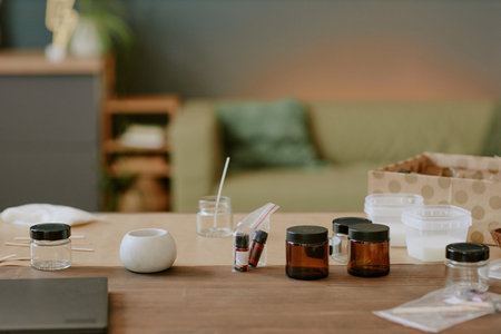 Several skincare products are being prepared on kitchen counter with jars and mixing tools scattered around. Background shows blurred home interiorの写真素材