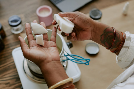 Close-up of hands crafting homemade soap with natural ingredients from above. This image captures...