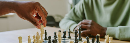 Hand of unrecognizable African American man moving white knight piece while playing chess game with...