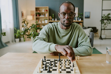 Medium shot of young African American chess player looking at camera while moving piece to solve problemの写真素材
