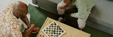 From above view of two young African American friends sitting in living room thinking over tactics...