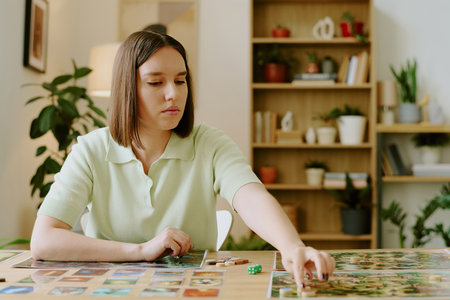 Medium shot of young Caucasian woman playing modern tabletop game at homeの写真素材