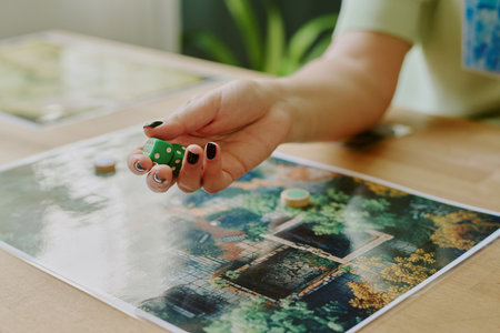 Hand of unrecognizable young woman holding dice while playing modern board game