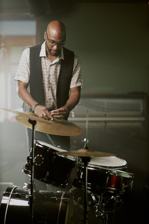 Vertical shot of young African American musician adjusting cymbal while assembling drum kit for performanceの写真素材