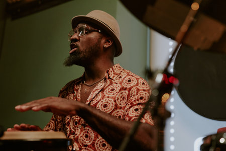 Confident African American man enjoying singing song while playing conga on stage in barの写真素材