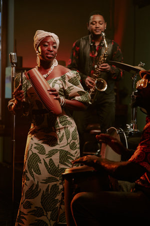 Vertical shot of Black men and woman playing in Afro-Cuban jazz band performing on stageの写真素材