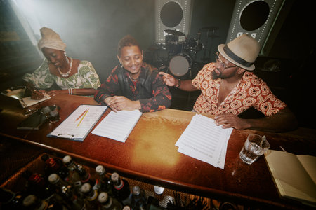 High angle view of modern African American jazz musicians working on new songs while spending evening in local barの写真素材