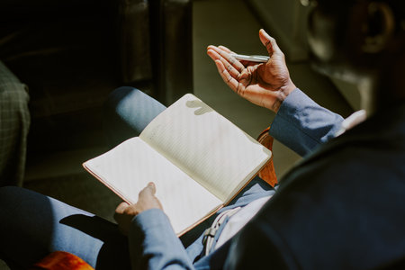 Close-up of person writing in notebook during business meeting with pen in hand and focused...