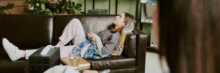 Woman reclining on sofa with closed eyes and relaxed posture. Cozy living room setting with plants,...
