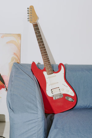 Vertical shot of red-white electric guitar on blue couch in roomの写真素材