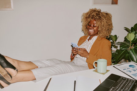 Young attractive woman texting in messenger while relaxing during shift in officeの写真素材