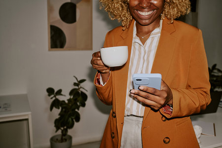 Unrecognizable woman chatting on social networks while having coffee break at workの写真素材