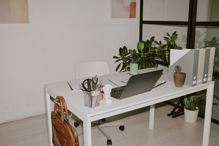 Office supplies and black laptop on white wooden table at home