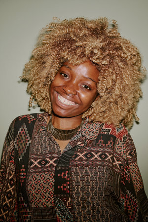 Portrait of blonde curly haired woman smiling widely while posing for photoの写真素材