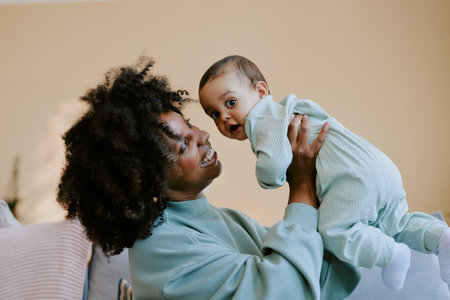African American mom admiring her baby boy and playing with him while baby looking at cameraの写真素材