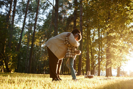 Low angle shot of African American granny and her grandson cuddling on meadow in parkの写真素材
