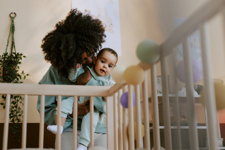 Low angle shot of curly-haired black mom kissing her baby boy on cheekの写真素材