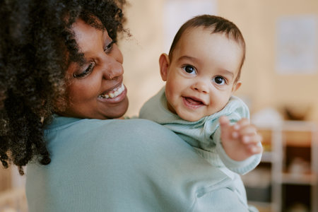 Little boy pulling his hand to camera while his African American mom hugging himの写真素材