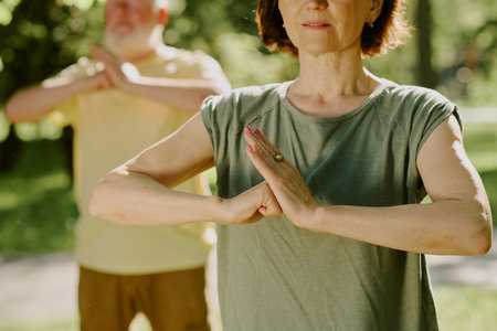 Medium close up of toned arms of senior woman in open hand vs closed fist position, senior man practicing same pose in blurred backgroundの写真素材