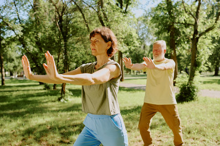 Senior focused couple doing karate set during open air training in park togetherの写真素材