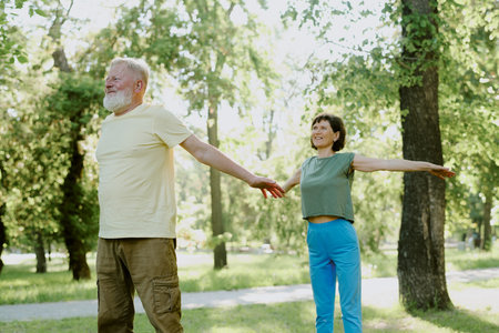 Senior husband and his wife warming up muscles and joints before yoga practice in parkの写真素材