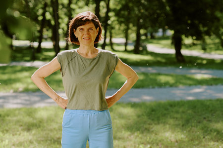 Portrait of smiling brunette woman dressed in cotton sportswear looking directly at camera while having open air workoutの写真素材