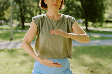 Medium close up of sporty senior woman during pose for improving coordination in parkの写真素材