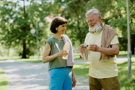Sporty senior couple resting and drinking pure water after cardio trainの写真素材