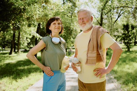 Proud senior couple smiling and posing for photo after cardio train in parkの写真素材
